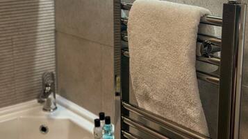 A bathroom with a sink, mirror, towel rack, and toiletries.