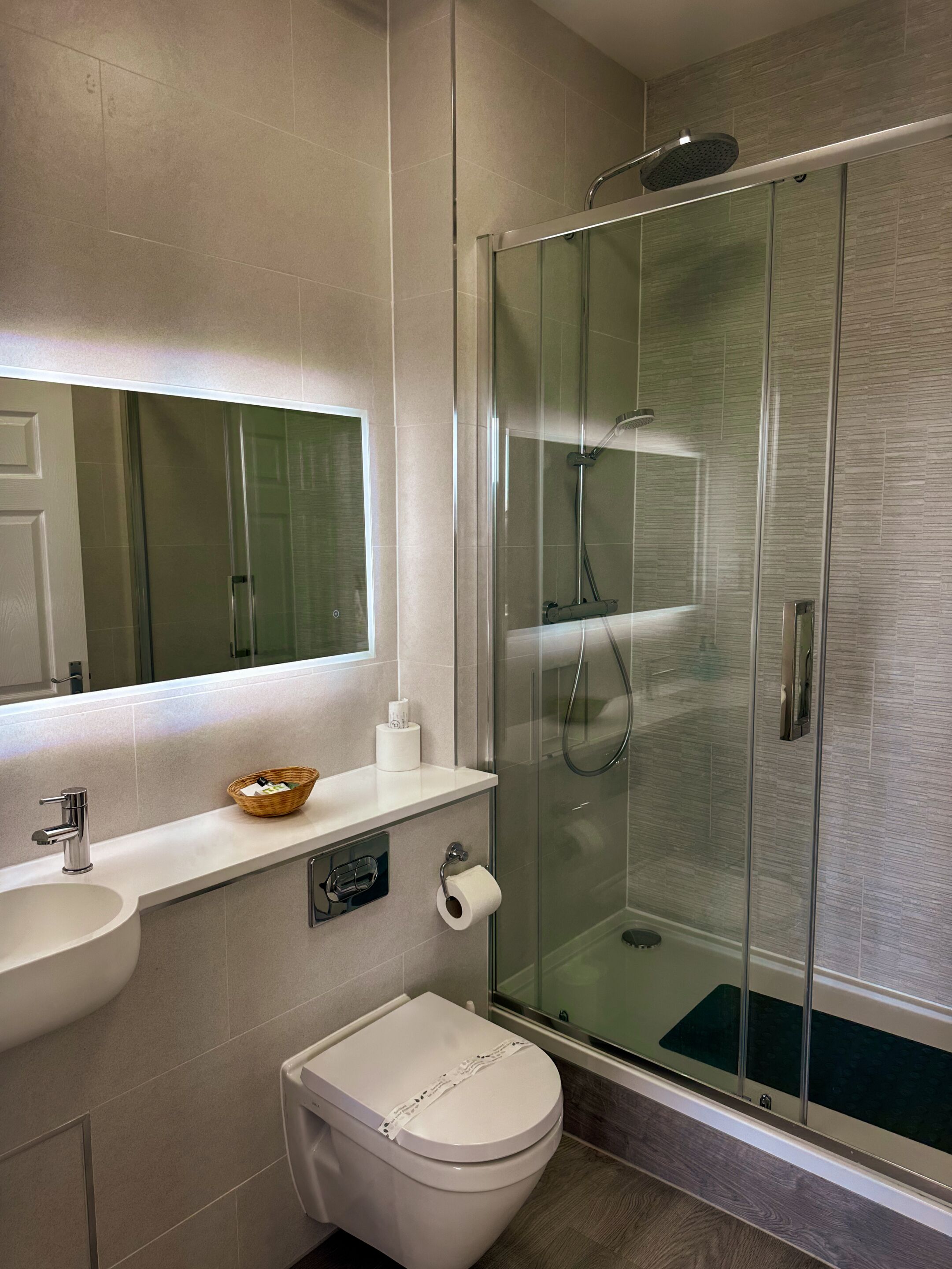 A modern bathroom with a glass-enclosed shower, a white sink, and a toilet.