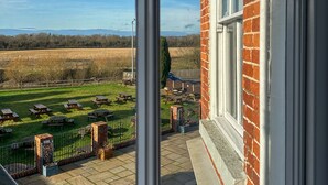 Blick aus einem Fenster auf eine Wiese mit Picknicktischen und ein Ziegelgebäude.