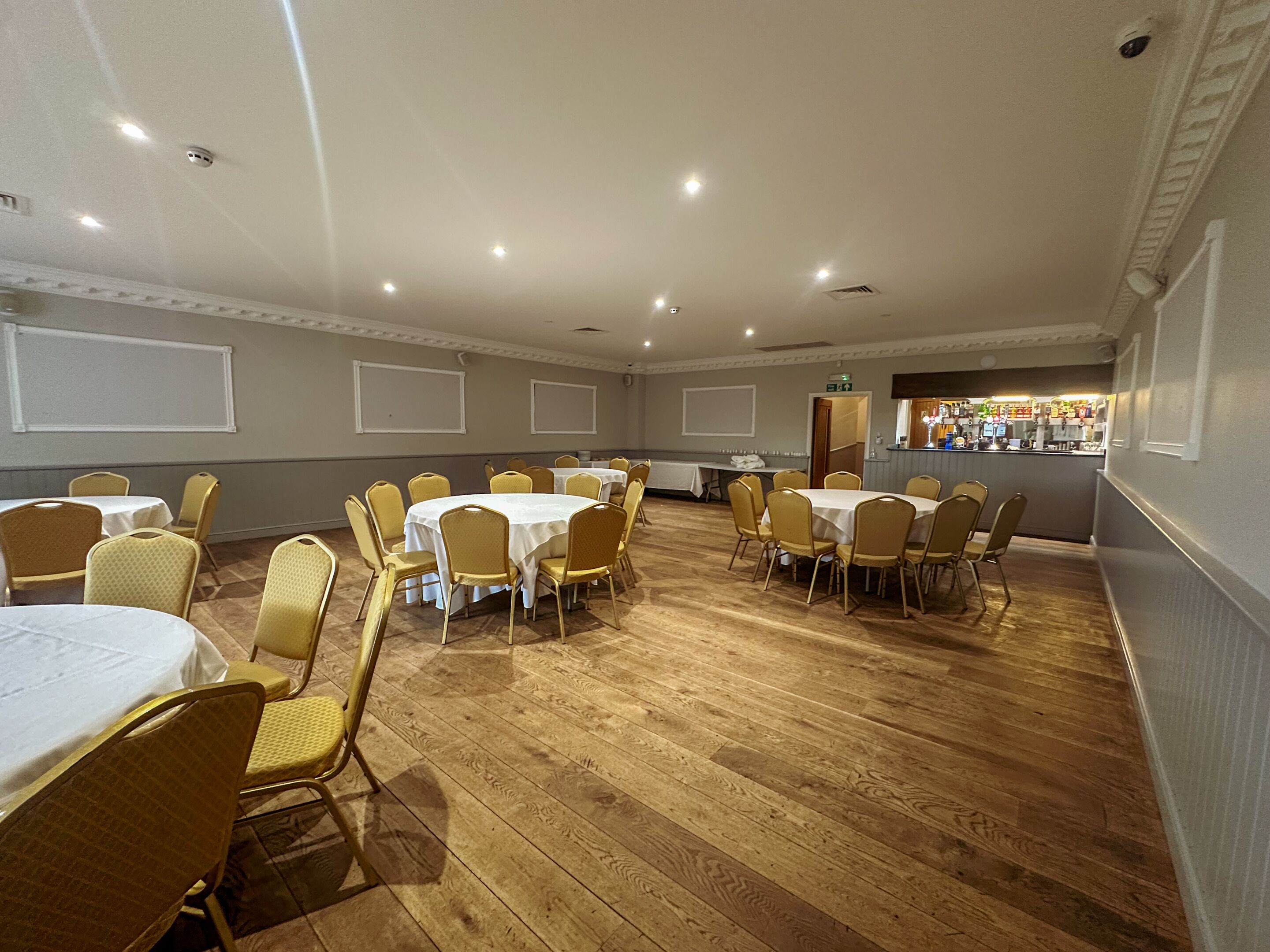A conference room with round tables and chairs, a bar area, and a whiteboard on the wall.