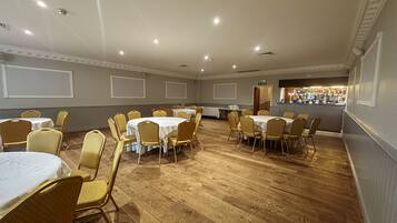 A conference room with round tables and chairs, a bar area, and a whiteboard on the wall.