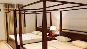 Una cama con dosel de madera, ropa de cama blanca y una mesita de noche con lámpara.