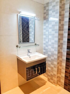 A bathroom with a white sink, a mirror, and a tiled wall. - Livinya Holiday Resort (Kataragama)