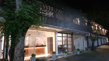 A modern building with a glass facade, a reception area, and potted plants along the entrance.