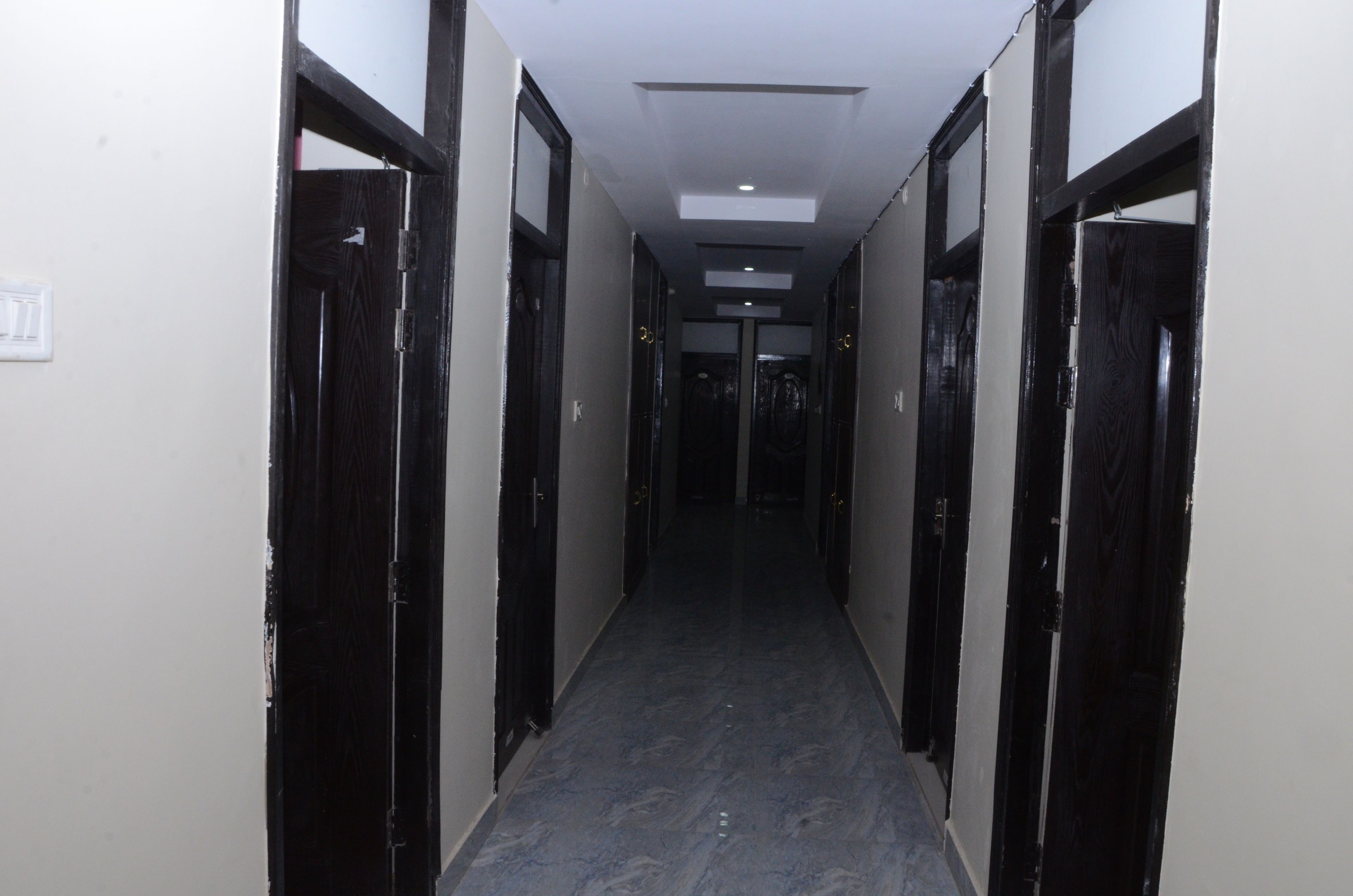 A narrow hallway with black doors on either side and a light-colored floor.