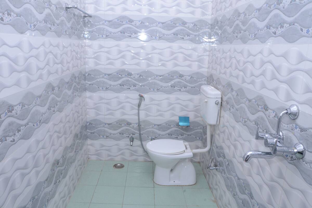 A bathroom with a wavy tile pattern, a white toilet, and a shower with chrome fixtures.