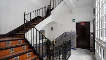 Una escalera con barandillas decoradas y baldosas estampadas, que conduce a un piso superior.