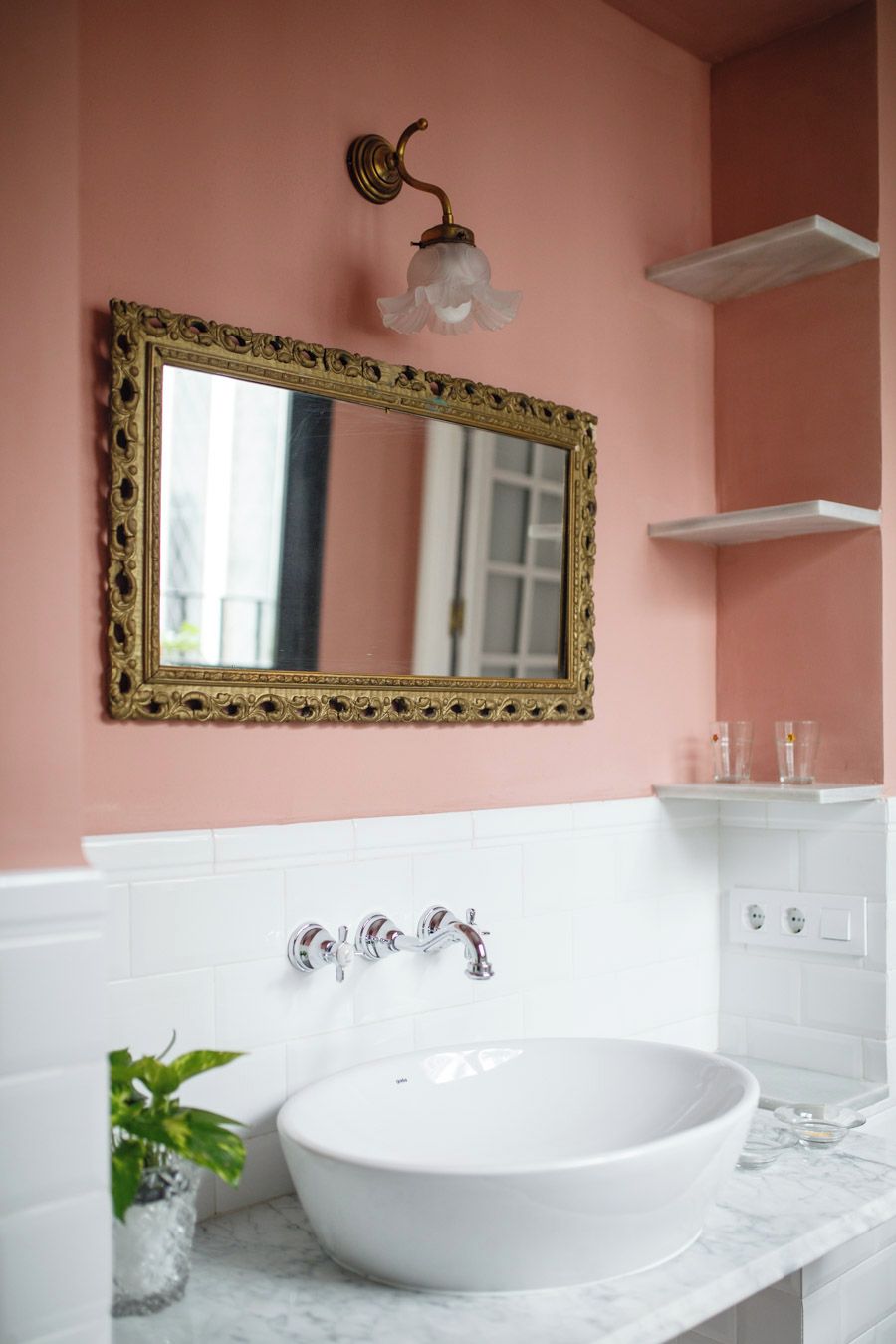A bathroom with a large ornate mirror, white vanity, and a single white basin.