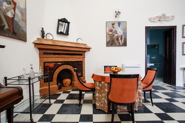 Un comedor con suelo a cuadros, chimenea y mesa con sillas.