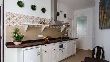 A kitchen with white cabinets, a built-in oven, a microwave, a sink, and a potted plant.