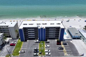 Un hotel de varios pisos con estacionamiento, vista al mar y zona de piscina.