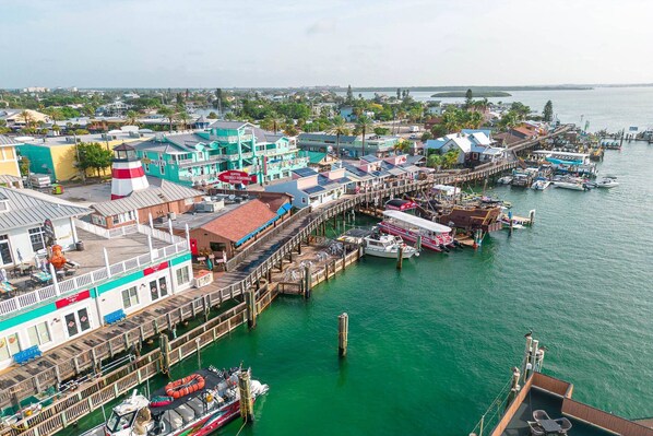 Zona costera con un muelle, barcos y diversos edificios, incluyendo un hotel y un restaurante de mariscos.