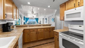 A modern kitchen with wooden cabinets, a large island, a built-in oven, and a view to the outside. - Superb Location on the Beaches of Madeira. Great Corner Unit Views. Beachfront Pool on the Sand! (Madeira Beach)
