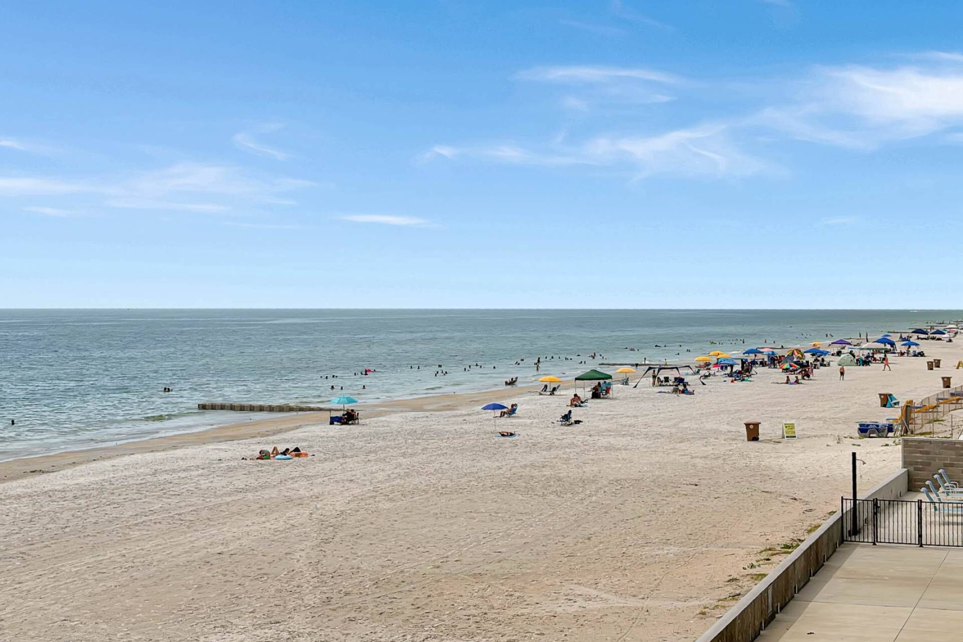 A beach with a sandy shore, umbrellas, and people.