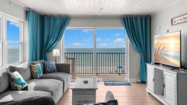A room with a sofa, a TV, and a view of the sea. - Superb Location on the Beaches of Madeira. Great Corner Unit Views. Beachfront Pool on the Sand! (Madeira Beach)