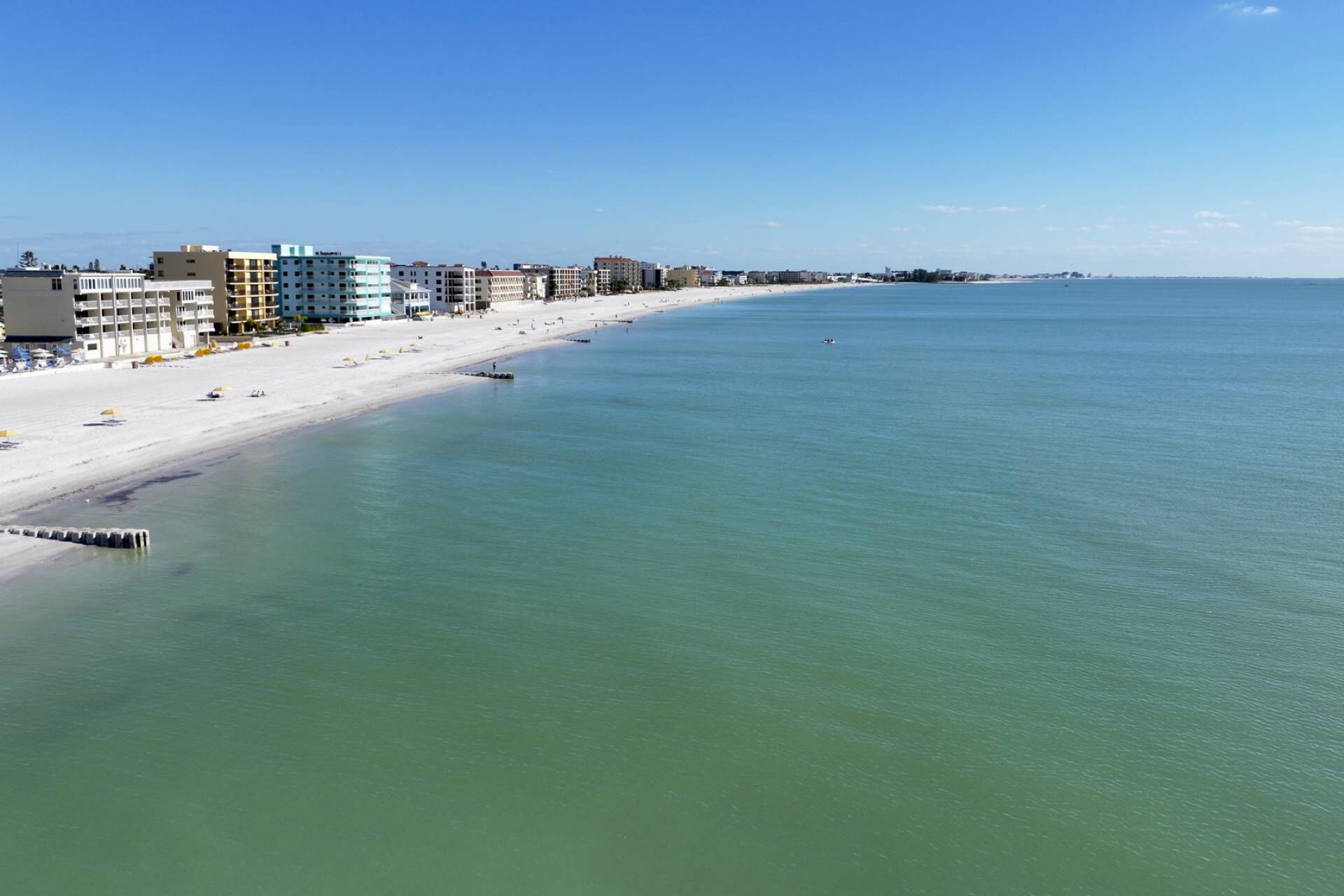 Un paysage urbain côtier avec une plage de sable, des bâtiments et une eau calme.