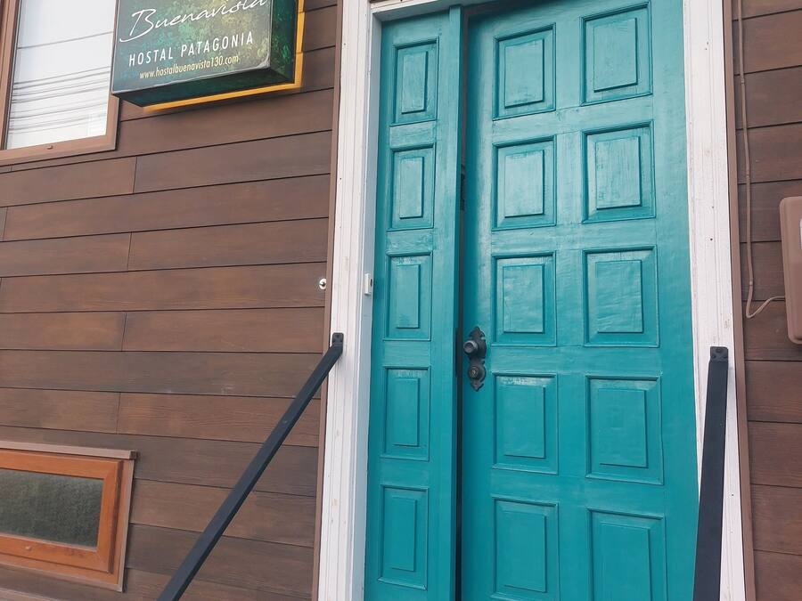 A teal double door with a white frame, a sign above it, and a wooden exterior wall.