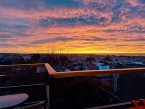 Un balcon donnant sur un quartier résidentiel, avec vue sur le coucher du soleil.