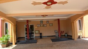 A covered entrance area with a tiled floor, framed artwork on the walls, and potted plants. - Glory Summit Hotel (Hoima)