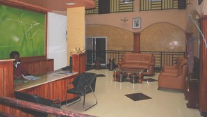 A lobby with a reception desk, seating area, and a staircase. - Glory Summit Hotel (Hoima)