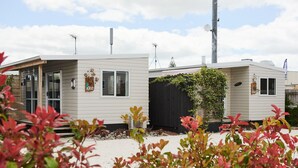 Een rij vakantiehuisjes met een overdekte veranda en een kleine tuin ervoor.