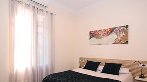 Een slaapkamer met een bed, nachtkastje, een wandlamp en een schilderij.