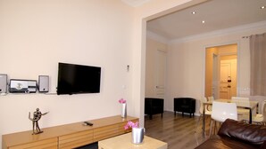 Een moderne woonkamer met een flatscreen televisie, een houten console en een leren bank.