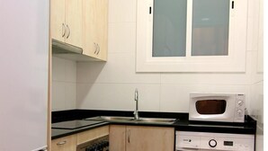 Een kleine keuken met een koelkast, fornuis, magnetron en vaatwasser.