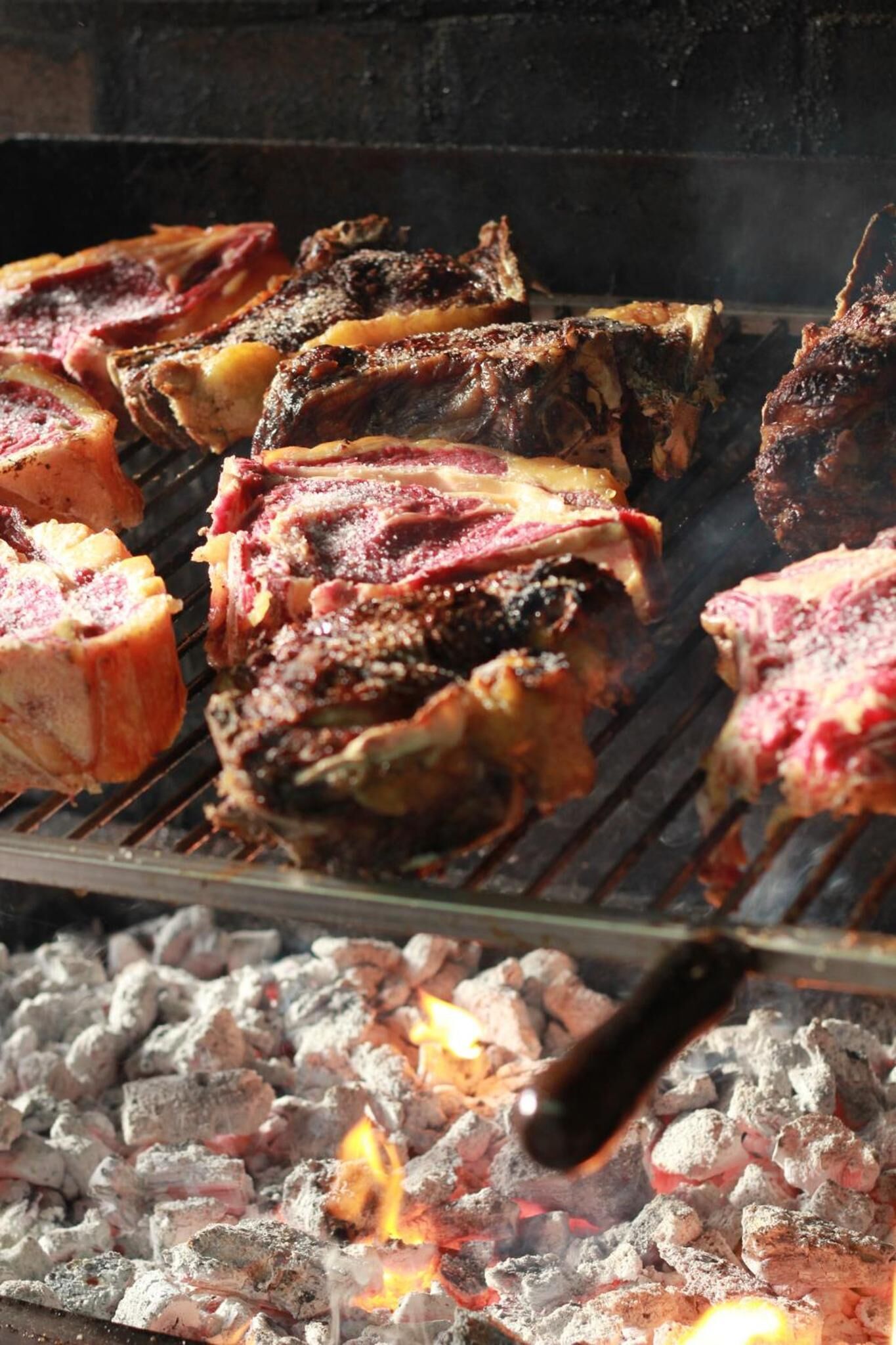 Una parrilla con diferentes carnes asándose sobre carbón.
