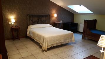 A bedroom with a bed, two bedside lamps, a chair, a small table, and a skylight.