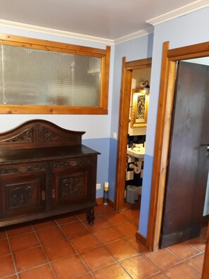 A room with a wooden dresser, a window with a wooden frame, and a tiled floor.