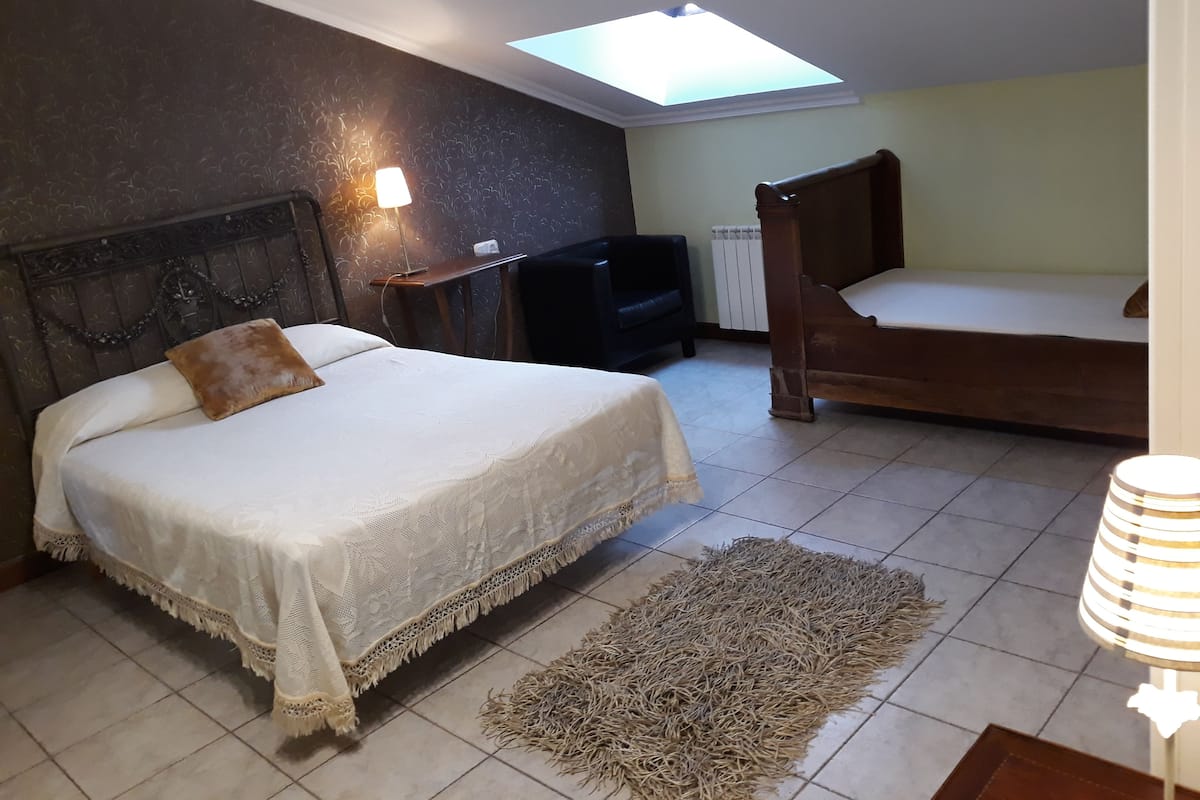 Ein Schlafzimmer mit Bett, Nachttisch, Lampe, Stuhl, Heizkörper und einem Oberlicht.