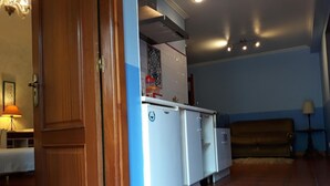 Een kleine keuken met een witte koelkast, een houten deur en een blauwe wand.