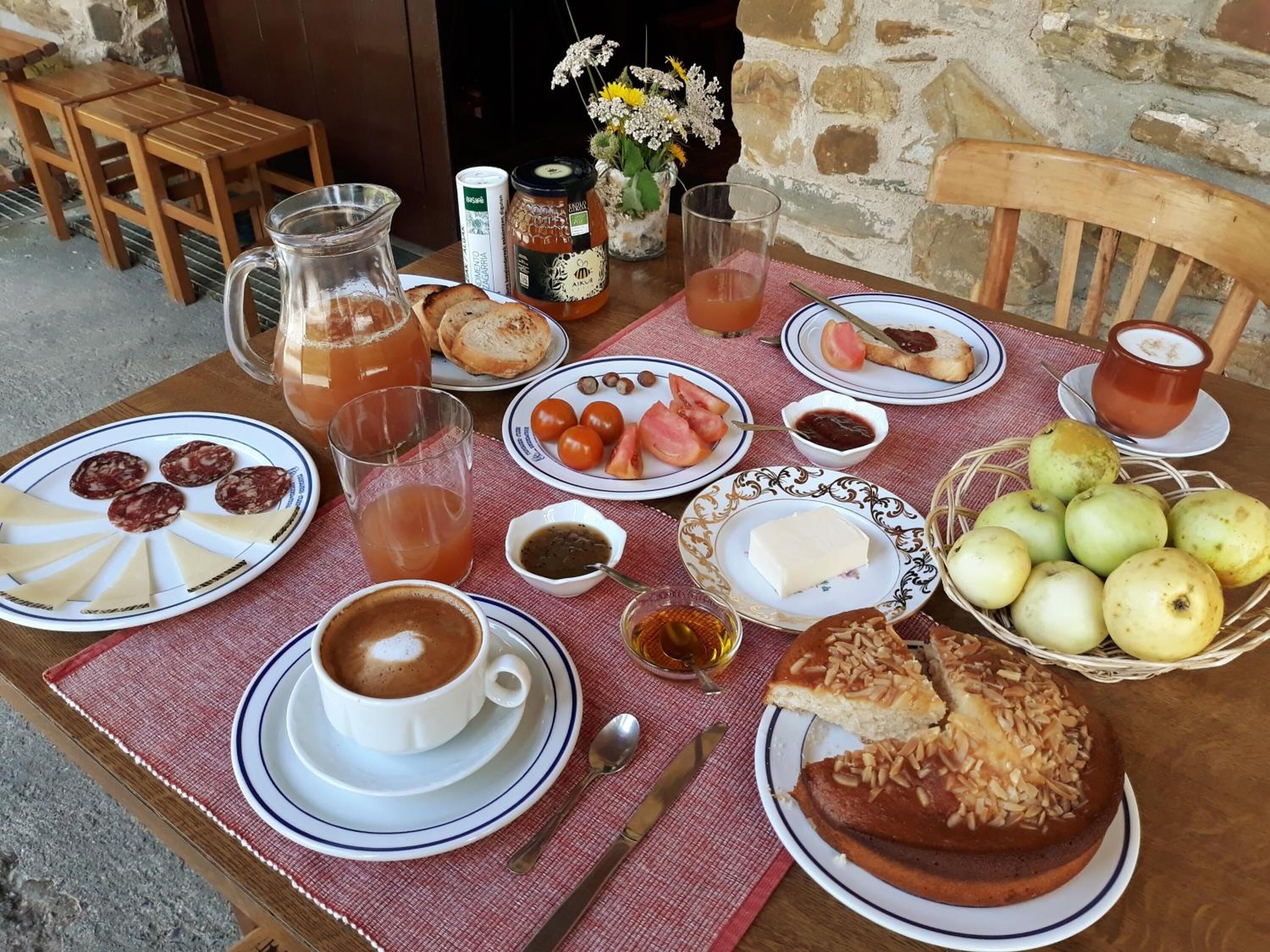 A breakfast setting with plates of food, a pitcher, a glass of juice, and a cup of coffee on a table.