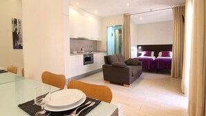 A modern apartment with a dining area, kitchenette, and a living space with a sofa and two beds. - CLASSBEDROOM BARCELONA BEACH 5 APARTMENT (Barcelona)