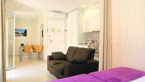 A hotel room with a bed, a sofa, a dining area with chairs, and a kitchen area. - CLASSBEDROOM BARCELONA BEACH 5 APARTMENT (Barcelona)