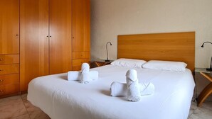 Hotellihuone, jossa on suuri sänky, puinen vaatekaappi sekä kaksi yöpöytää, joissa on lamput.