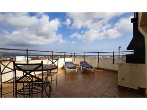 Une terrasse sur le toit, avec deux chaises longues et une table, d’où l’on peut admirer la vue sur la ville.