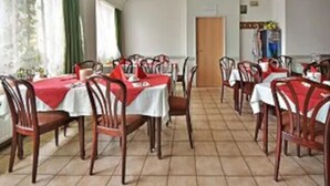 Un comedor con varias mesas cubiertas con manteles rojos y sillas de madera.