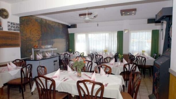 Un área de comedor con varias mesas y sillas, una barra central y un cuadro grande en la pared.