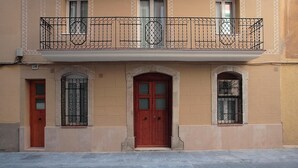 A building with a red door, two windows with metal bars, and a balcony with a wrought iron railing. - CLASSBEDROOM BARCELONA BEACH 2 APARTMENT (Barcelona)
