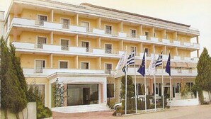 A multi-story hotel with balconies, a central entrance, and flags. - Hotel Philippos (Livadia)