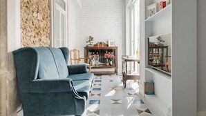 A modern living room with a blue sofa, a wooden coffee table, and a bookshelf. - GuestHouse - Deluxe Double Room with Balcony (Room 8 Seraphim ) (Lisboa)