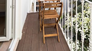 A balcony with a wooden table and chairs, a white railing, and a view of a red-roofed building. - GuestHouse - Deluxe Double Room with Balcony (Room 8 Seraphim ) (Lisboa)