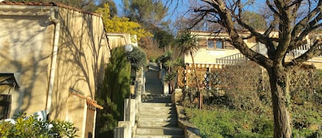 A stone staircase leading up to a building with a tiled roof, surrounded by greenery and trees.