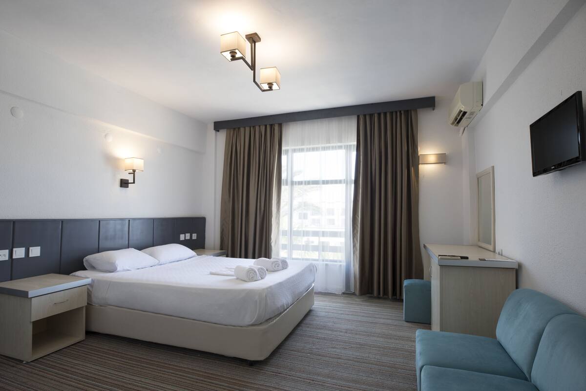 Une chambre d’hôtel comprenant un lit, des tables de chevet, une télévision, un bureau et une chaise.