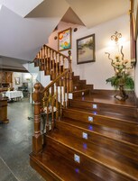 Una escalera de madera con barandilla que lleva a un rellano con un cuadro enmarco y un accesorio de iluminación decorativo.
