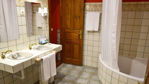 Un baño con dos lavamanos, una bañera y un cortinero de ducha.