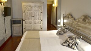 Un dormitorio con cama, dos almohadas, una mesita de noche, un armario y una televisión.