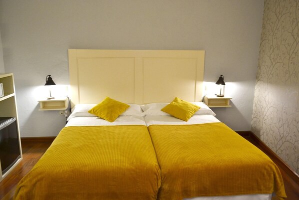 A double bed with two yellow pillows, a white headboard, and two bedside lamps. - Alda Vía León (León)